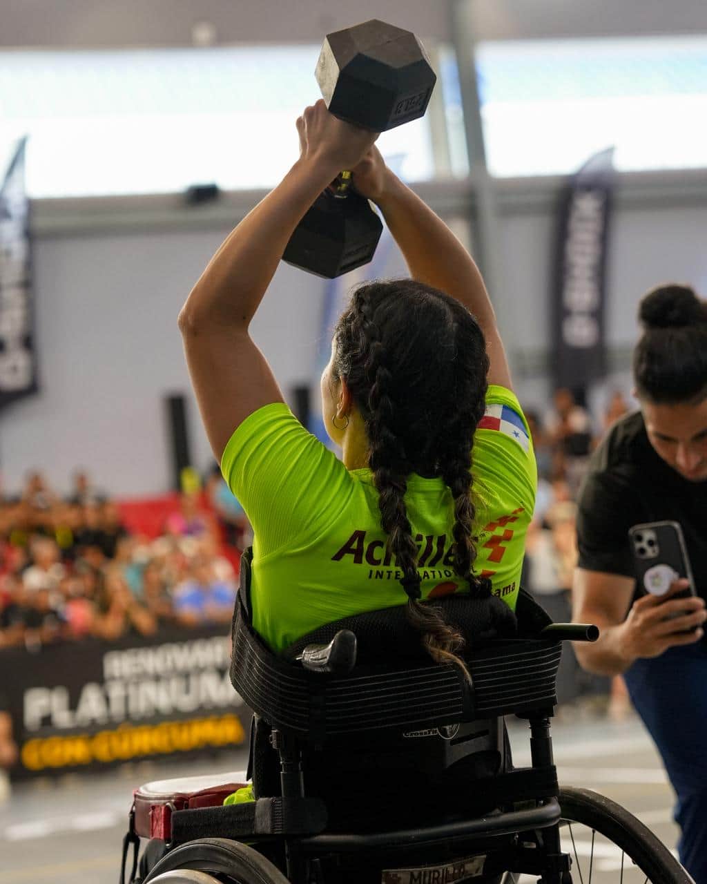 Una atleta levanta una mancuerna por encima de la cabeza desde su silla de ruedas